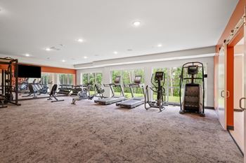 a gym with exercise equipment on the floor and large windows